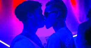 This article is about how dating apps impact queer spaces. In the photo, two people kissing in a nightclub.