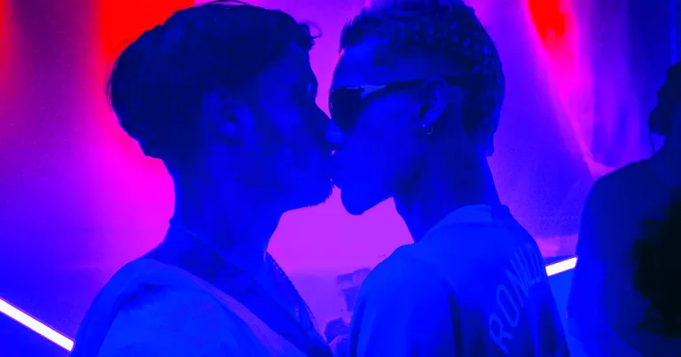 This article is about how dating apps impact queer spaces. In the photo, two people kissing in a nightclub.