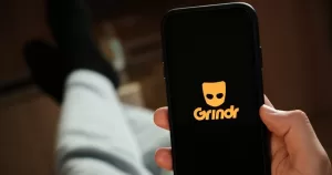 This article is about an Irish gay man targeted on Grindr. In the photo, a person holding a phone with the Grindr logo on the screen.