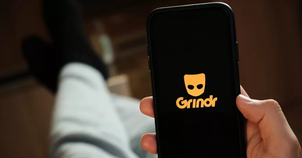 This article is about an Irish gay man targeted on Grindr. In the photo, a person holding a phone with the Grindr logo on the screen.