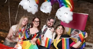 People hold rainbow flags and balloons as they celebrate at Belong To's award ceremony celebrating youth services working with LGBTQ+ youth.