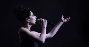 Photo of Naomi Banks, who will take part in the RTÉ Concert Orchestra's Love, Loss and Lipstick: A Valentine's Cabaret, singing into a microphone in the dark.