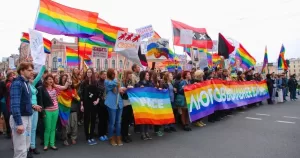 This article is about LGBTQ+ activists being targeted with Russia's undesirables law. In the photo, LGBTQ+ activists protesting and holding Pride flags, banners and signs in Russia.