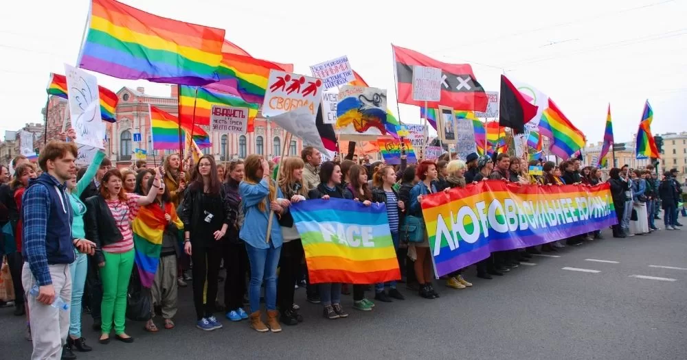 This article is about LGBTQ+ activists being targeted with Russia's undesirables law. In the photo, LGBTQ+ activists protesting and holding Pride flags, banners and signs in Russia.