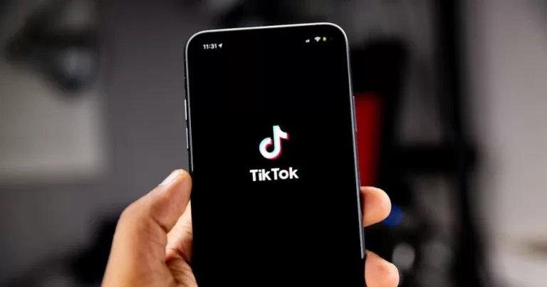 This article is about TikTok US collective sensitive information. In the photo, a hand holding a phone with the TikTok logo on the screen.