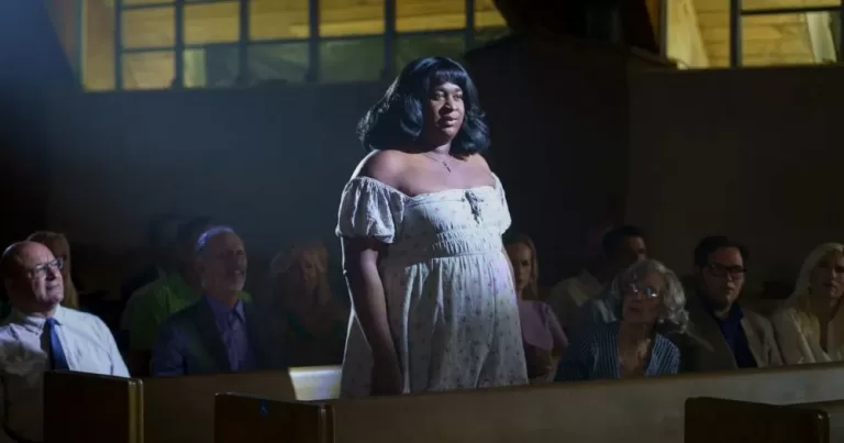 Terri Joe stands in a pew in dimly-lit church.