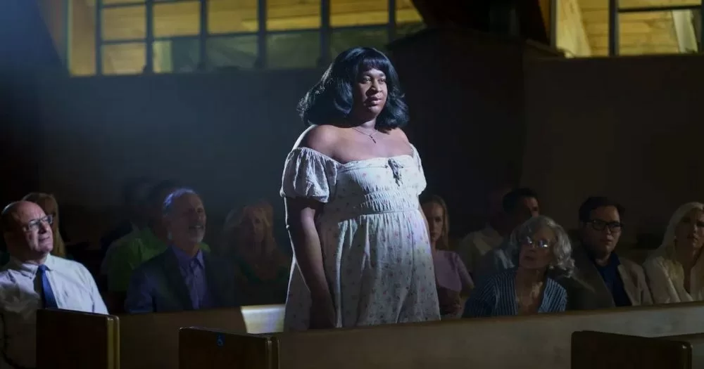 Terri Joe stands in a pew in dimly-lit church.