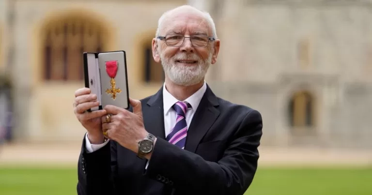 Martyn Butler holds his OBE in an outdoor setting.