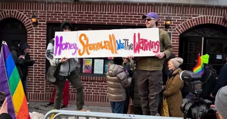 Image shows a protest sign being held by two people outside Stonewall. the protest was in response to the removal of the sites Pride flag. The sign reads " Honey, Stonewall was the warning"