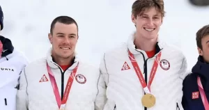 Jake Adicoff and his guide Reid Goble stand at the podium with gold medals around their necks.