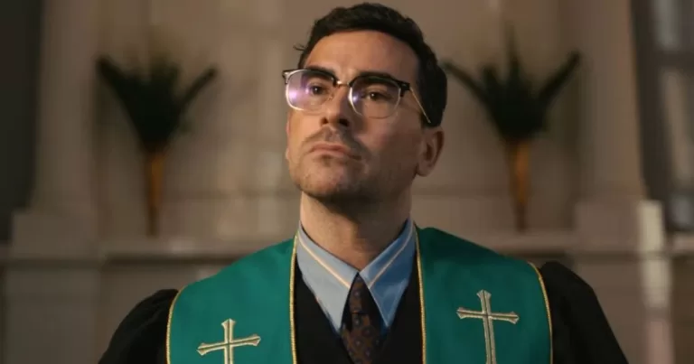 Actor Dan Levy dressed at a pastor, standing at an alter.