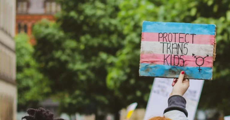 this article covers California schools blocking privacy for trans students. The poster above reads "protect trans kids'