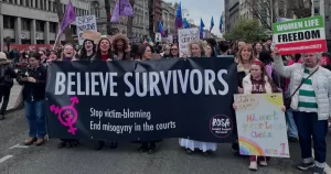 Last years march for International Women's Day holding a sign that reads "belive survivors". Preparations are being made for International Womens Day 2026.