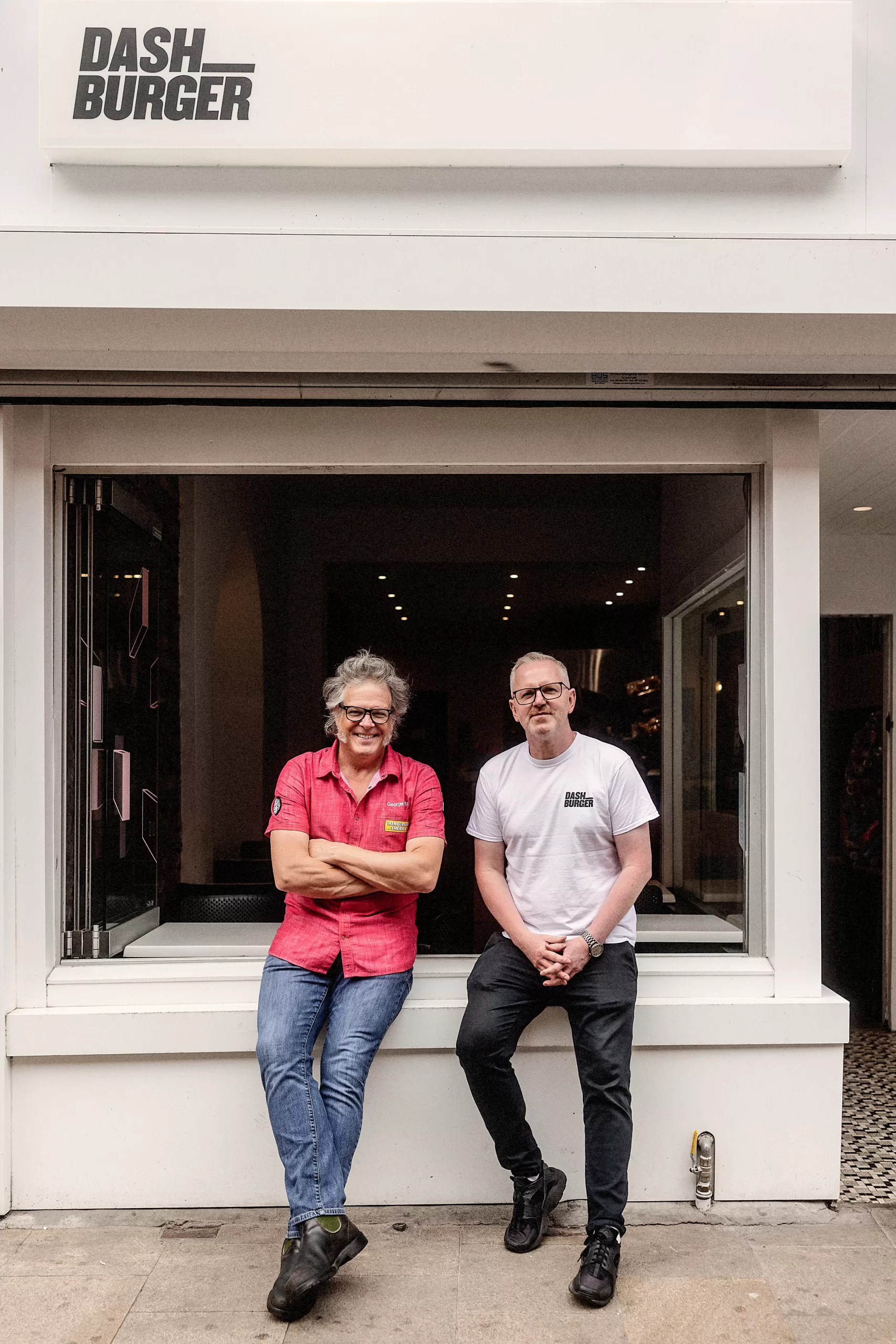 Two men stand outside a shop with a sign that reads Dash Burgers.