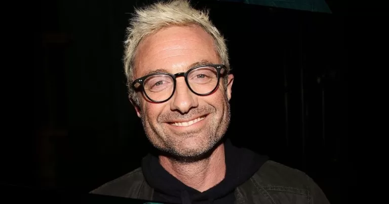 Jacob Tierney's Heated Rivalry follow up about Alexander the Great announced. A portrait photgraph of Jacob Tierney with bleach blonde hair, black-rimmed glasses, and lovely smile.