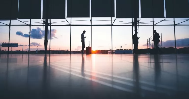 A person stands alone in an airport. This image is being used to represent a story about trans people whose visas may be at risk.