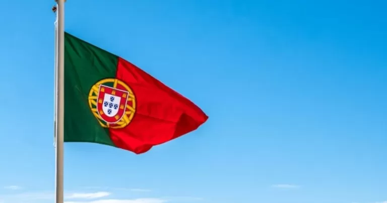 This article is about anti-trans bills advanced in Portugal. In the photo, a Portuguese flag flying in the sky.