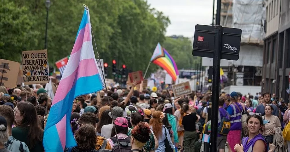 This article is about transphobia in UK media. In the article, people marching in the streets carrying trans and Pride flags.