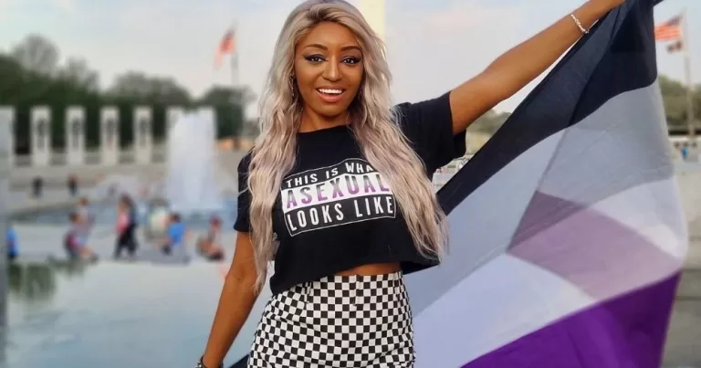Yasmin Benoit, asexual activist holding the ace flag and wearing a tee that says "this is what an asexual looks like". Asexual acceptance declines.