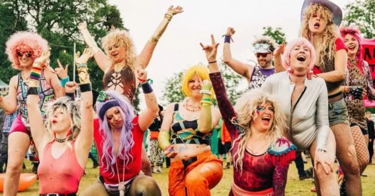 A crowd dressed in colourful outfits and wigs at Beyond the Pale cheers and celebrates together.