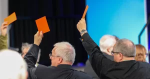 Members of the Church in Wales voting on blessings for same-sex couples. People hold up coloured cards to signify their vote.