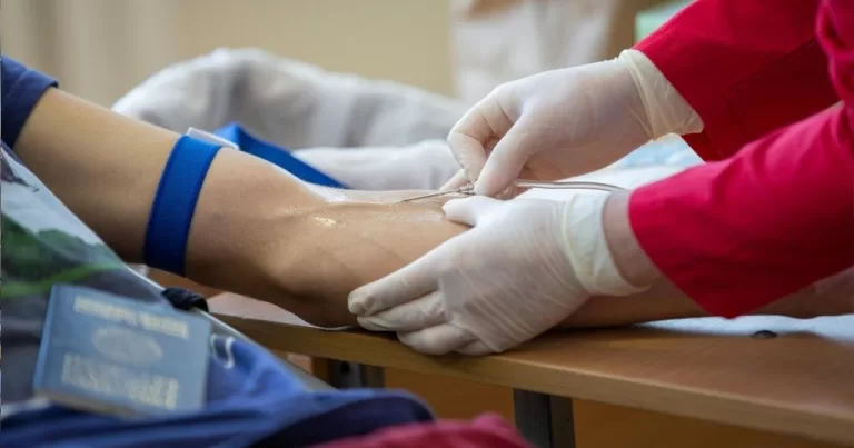 The article is about a new rule in Australia allowing LGBTQ+ people to donate blood. The image shows a person donating blood.