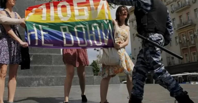 An officer rips a Pride flag away from protesters, this article covers Russian extremist labels on LGBTQ+ groups.