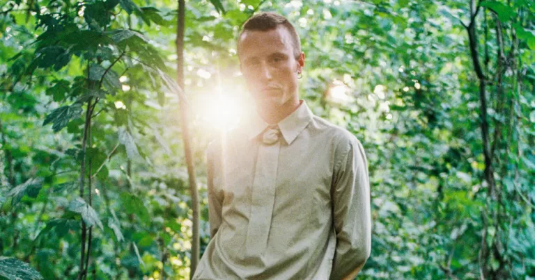 An image from Cruising Archaeology II: Eurotrash - A man posing in a green area.