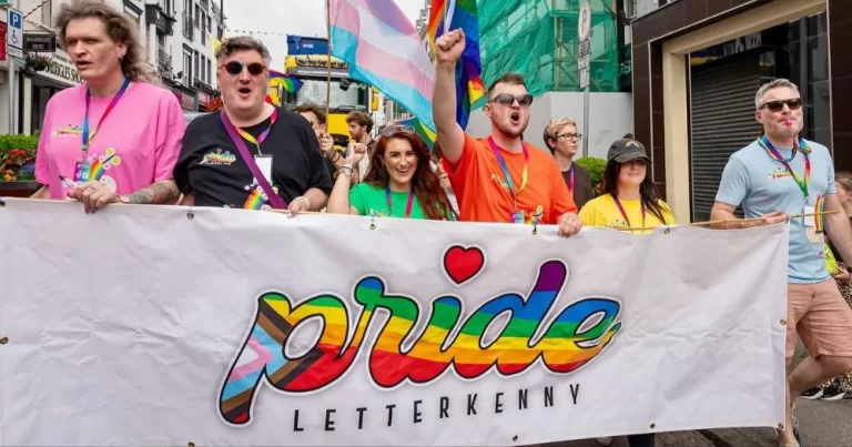 A group of people march behind a banner reading "Pride Letterkenny".