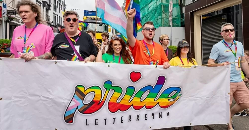 A group of people march behind a banner reading "Pride Letterkenny".