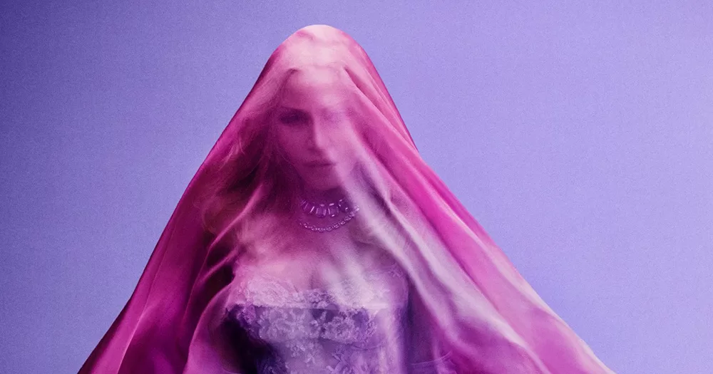 A cropped version of the cover art for Madonna's new album Confessions II. She poses in front of a purple background with a pink veil over her face.