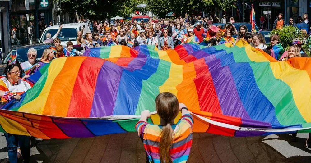 Parade-goers holding a large rainbow flag at Mayo Pride 2025.