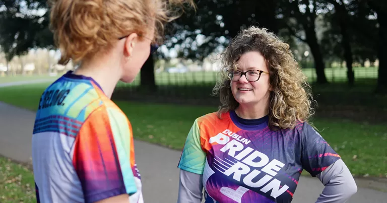 Promotional image of two people chatting in 2026 Dublin Pride Run t-shirts.