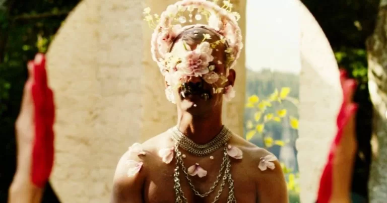 A person decorated in flowers and jewellery sits in front of a mirror in a scene from one of QSFF's 2025 festival films.
