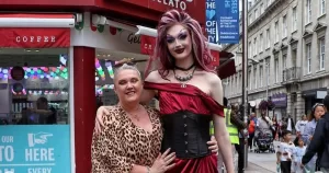 Noah, a young drag performer, poses on the street in drag with his mother.