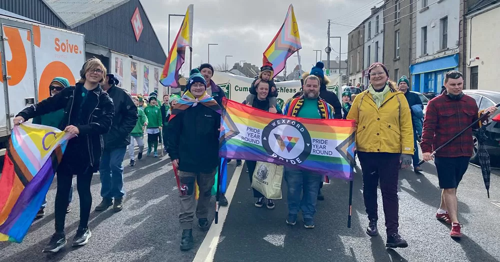 Wexford Pride members holding rainbow flags in a parade.