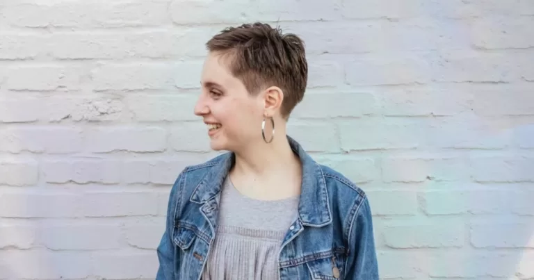 This article is about agender identities. In the photo, a person with short hair laughing and looking away from the camera.