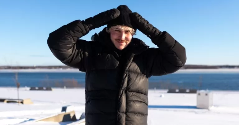 Photo from a Canadian version of Elska. It shows a man with a hat and puffer jacket with snow in the background.