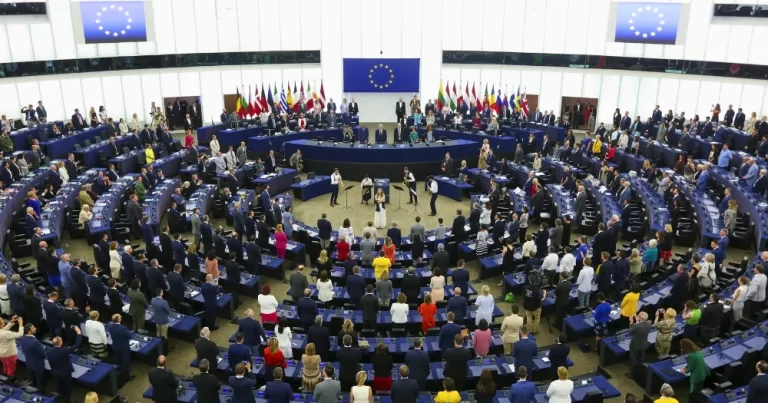The European Parliament, which has voted in favour of a EU-wide ban on conversion therapy, with MEPs standing in front of their seats.