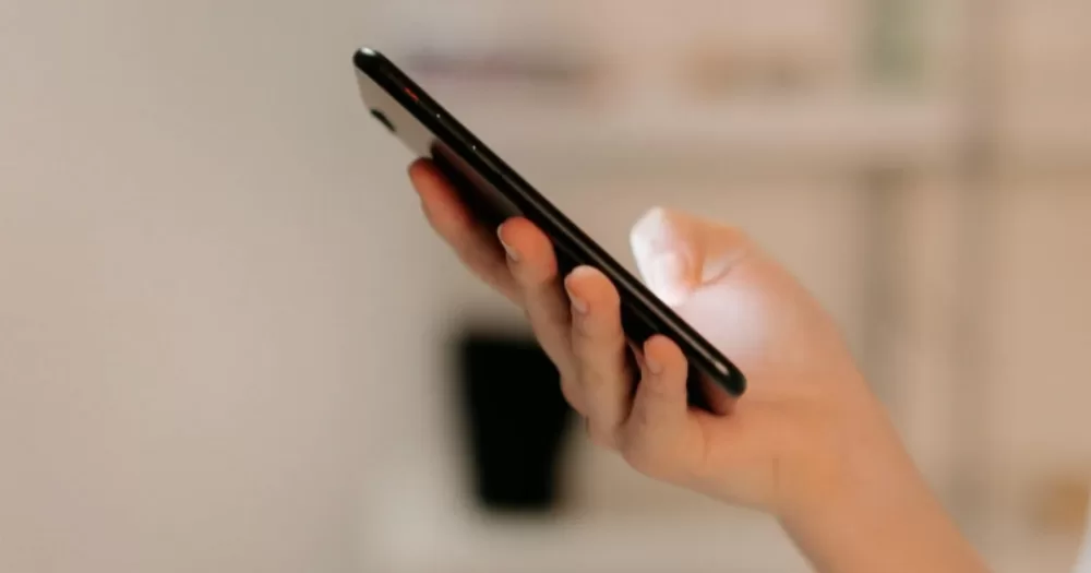 A person checking a phone. This article covers a Christian mobile network.