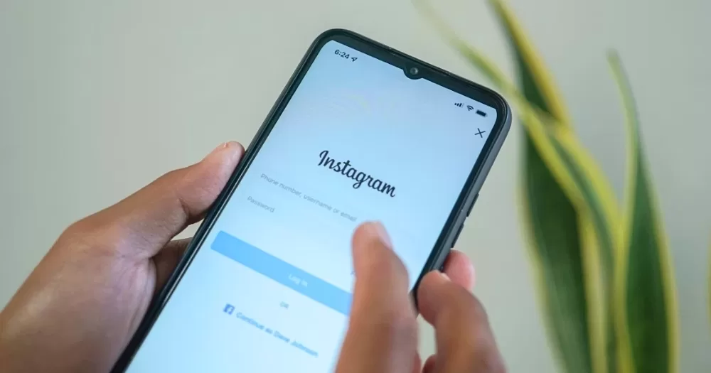 This article is about Meta facing backlash over LGBTQ+ censorship. On the photo, the hand of a person holding a phone with the app Instagram visible on the screen.
