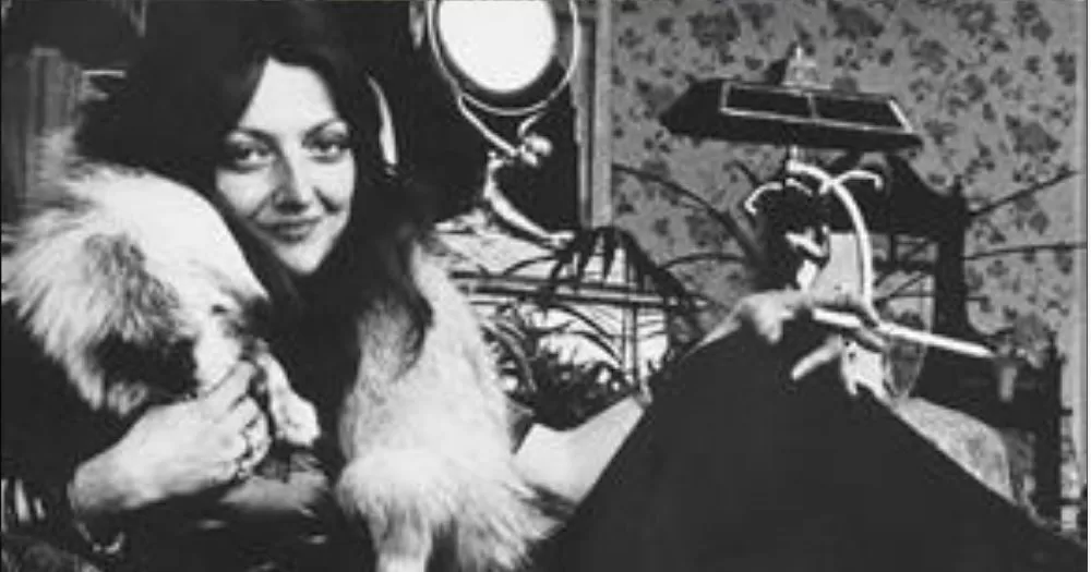 A portrait of owner of Shellys Leg, Shelly Bauman, is looking at the camera while smiling. She is wearing a fur coat and has dark hair