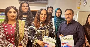 Group photo of Gender Interactive Alliance, a trans charity in Pakistan. There are six people in the image some holding a piece of paper.