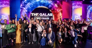 This article is about the 2026 GALAS shortlists. In the photo, a group of people posing on a stage while cheering and laughing, with the GALAS Awards logo in the background.