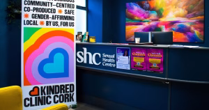 The hall of Sexual Health Centre Cork with a banner about Kindred Clinic, Ireland's first peer-led trans healthcare pilot service.