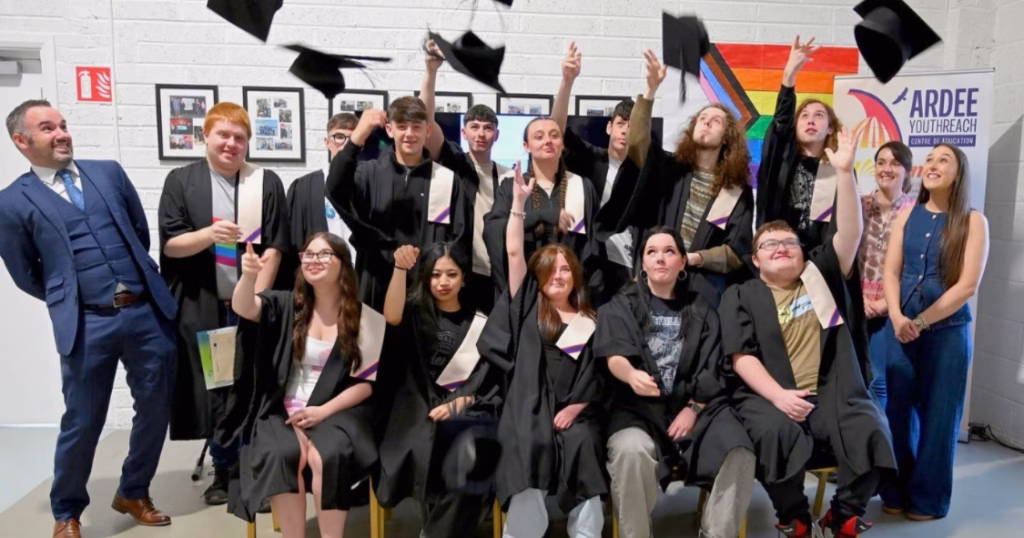 This article is about the Louth and Meath Education and Training Board. In the photo, a group of students and professors pose for a photo while throwing their graduation hats into the air.