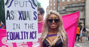 This article is about an asexual activist discussing conversion therapy and healthcare. In the photo, asexual activist Yasmin Benoit at a Pride parade posing with a sign that reads "Put asexuals in the Equality Act".