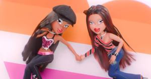The image depicts Bratz lesbian couple Roxxi and Nevra laying on a heart that has the lesbian flag colours