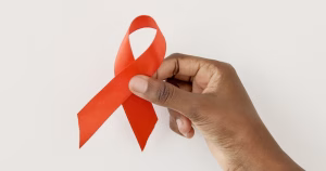 This article is about a new HIV campaign in Northern Ireland. The image shows a hand holding a red ribbon.