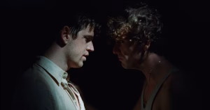 A still from the La Bola Negra trailer showing the side profiles of two men facing each other.